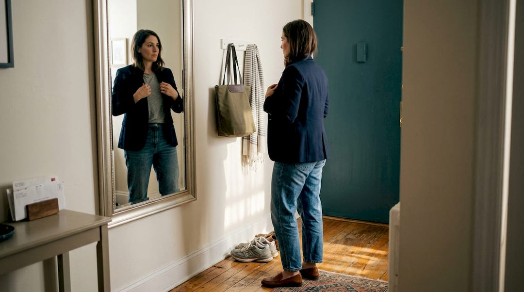 Woman refining personal style in entryway mirror