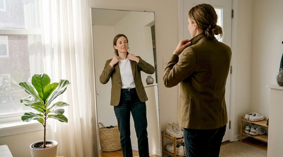 Woman adjusting sustainable outfit in living room mirror