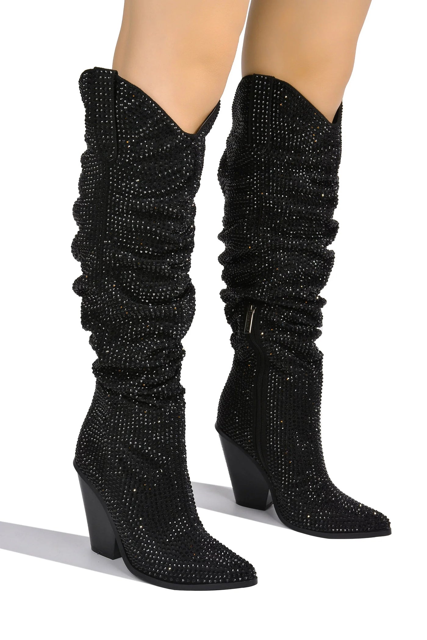 Detailed view of shimmering black rhinestone cowboy boots with a pointed toe and unique V-shaped opening at the calf, highlighting the texture and sparkle.