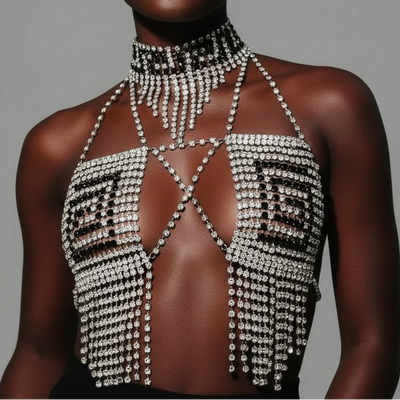Model wearing a sparkling, sheer top with intricate detailing against a gray background