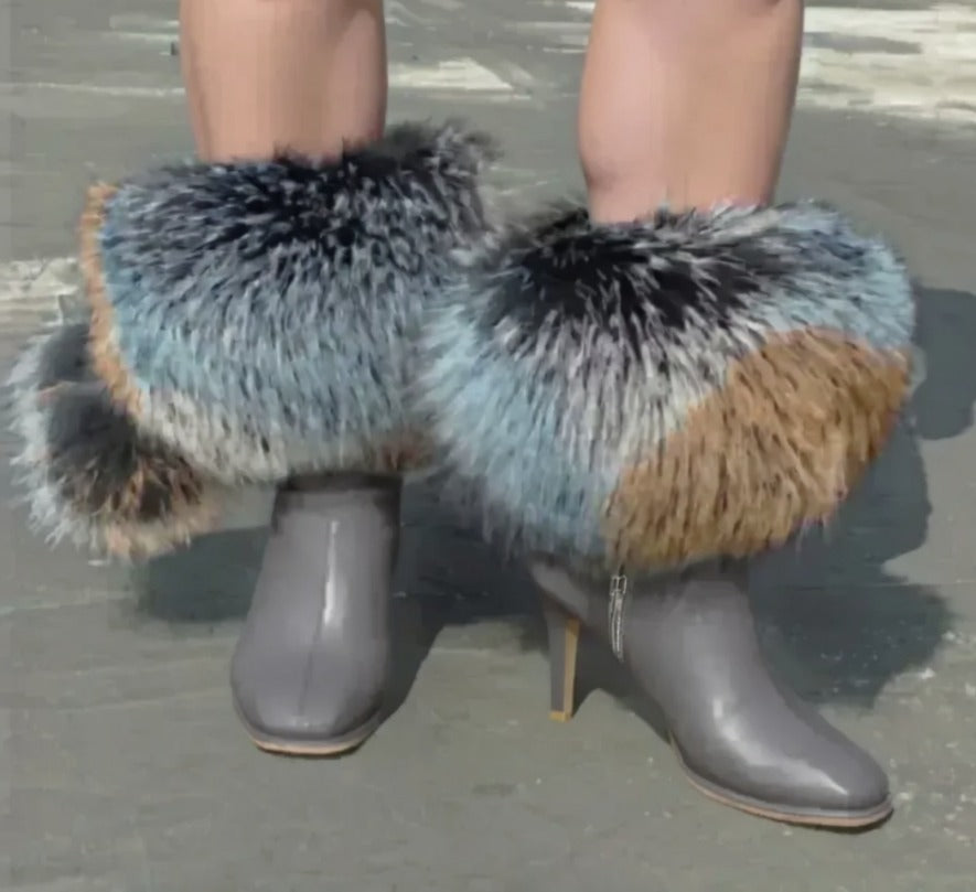 A pair of gray high-heeled boots with fur trim, worn by a person standing on a concrete surface.