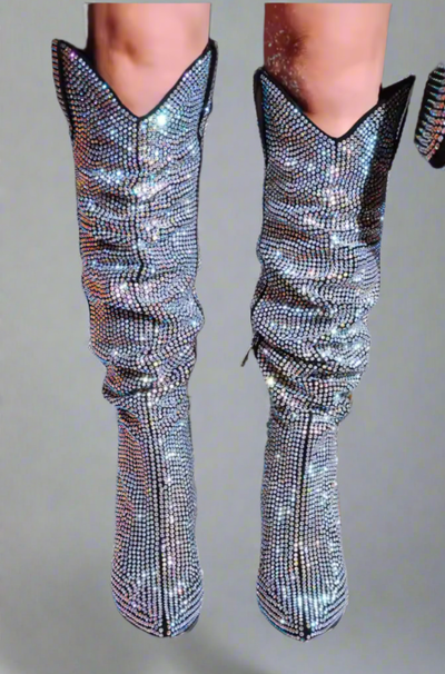 Detailed view of shimmering rhinestone cowboy boots with a pointed toe and unique V-shaped opening at the calf, highlighting the texture and sparkle.