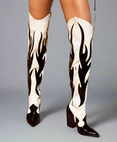 Pair of white, over-the-knee cowboy boots featuring a distinctive black flame design, pointed toes, and partial side zippers